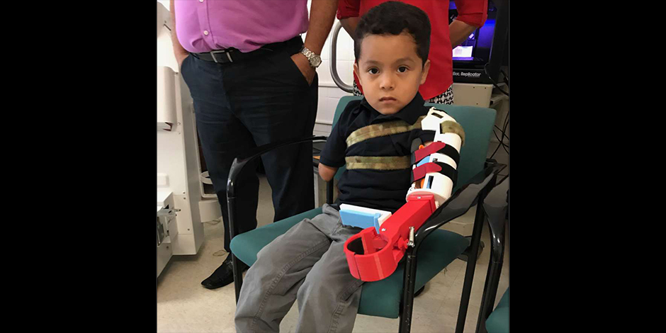 Isaac Cruz showcasing his new prosthetic hand. The device was created using 3D printing technology and custom-designed to fit Isaac’s upper arm. Photo: Pedro F. Frisneda/El Diario