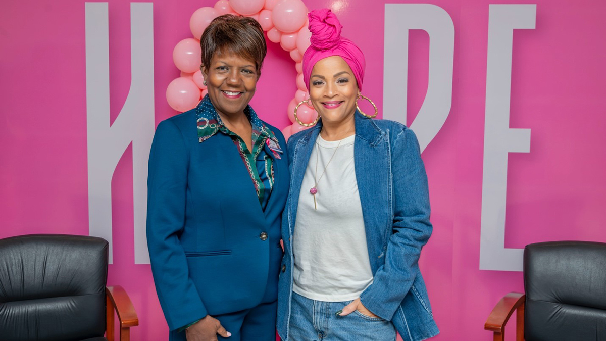 Two women standing in front of a pink sign

AI-generated content may be incorrect.