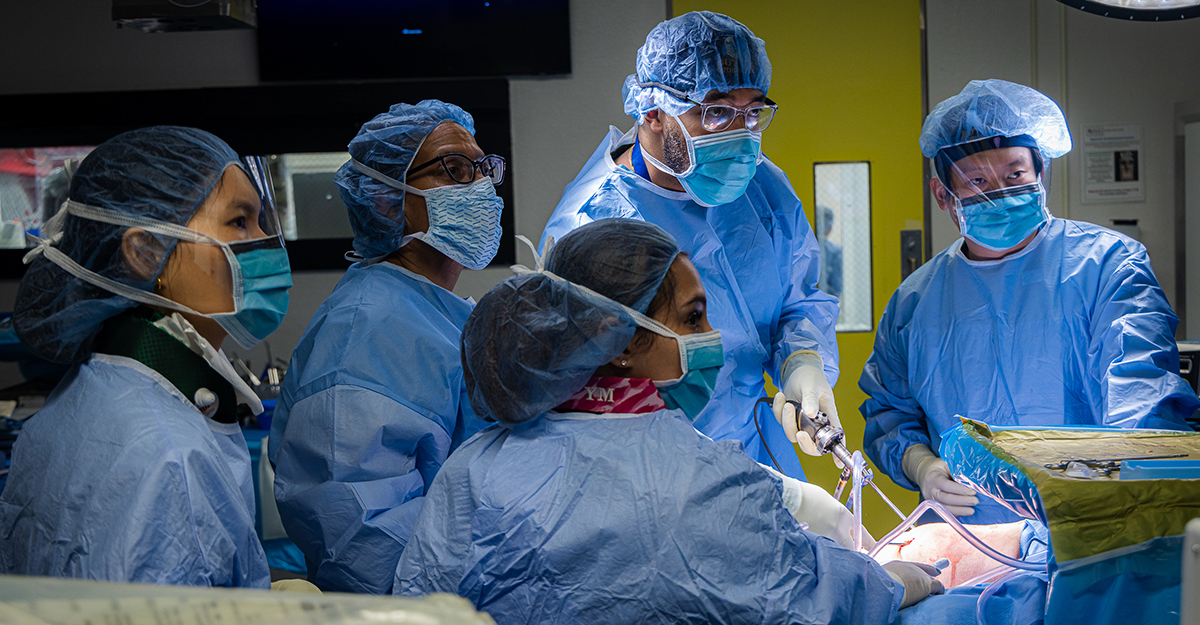 Mentorship meets mission. Surgical residents, Dr. Jack Zhong (first from right) and Dr. Samuel Montgomery (second from right) gain valuable hands-on experience in surgery and build confidence with Dr. McLaurin close by as their guide. Far left, Hye Jeong Yang, RN, middle foreground, surgical technician, Yasmin Missaoui.