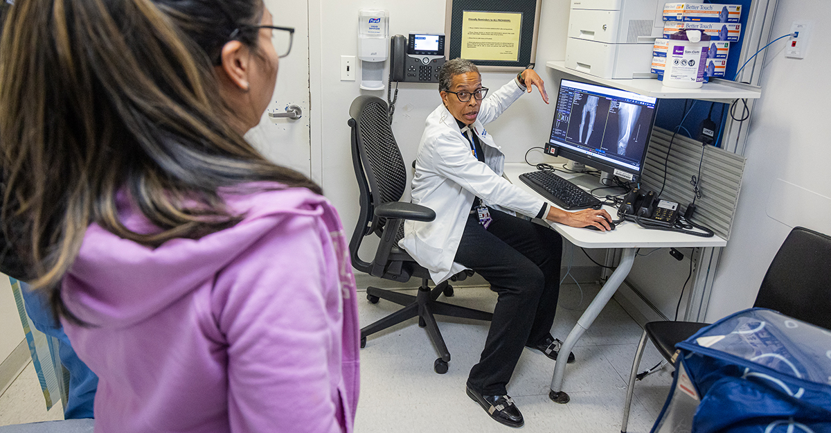 Post-procedure follow-up. Dr. McLaurin discusses the healing process with a patient. One of the most important things she monitors is bone healing, a signal of positive recovery.