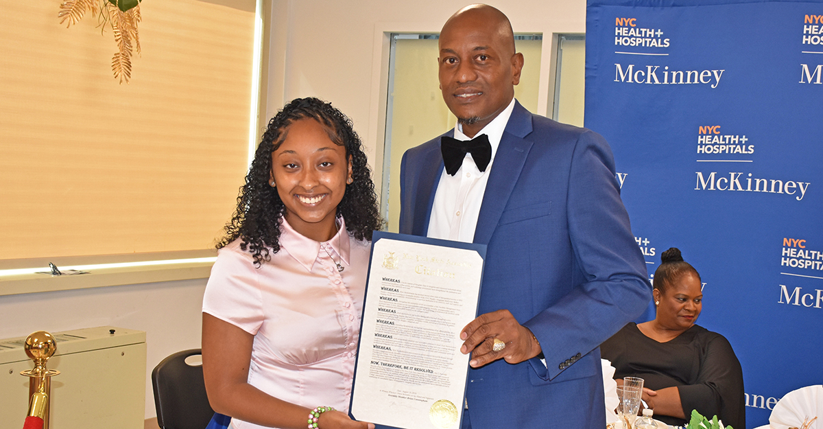 Director of Community and Constituent Affairs Aaomi Sai Ling from the Office of NYS Assemblymember Brian Cunningham presents Kurt Bartholomew with a citation recognizing his contributions to NYC Health + Hospitals/McKinney.