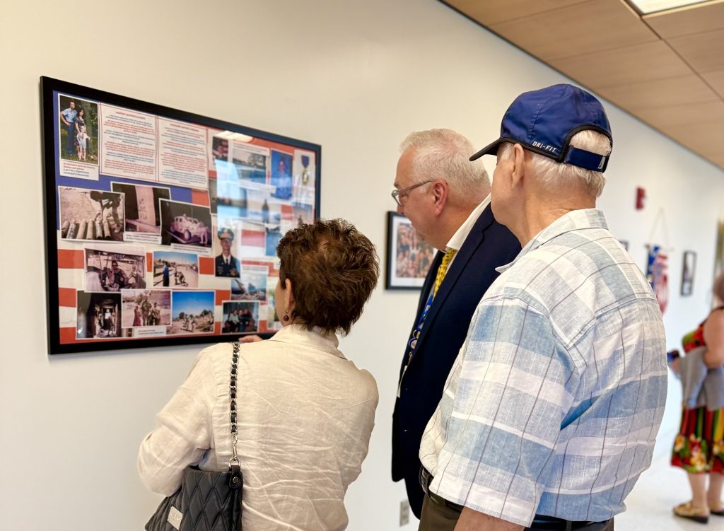 Exhibition attendees examine a collage dedicated to one family member’s military service.