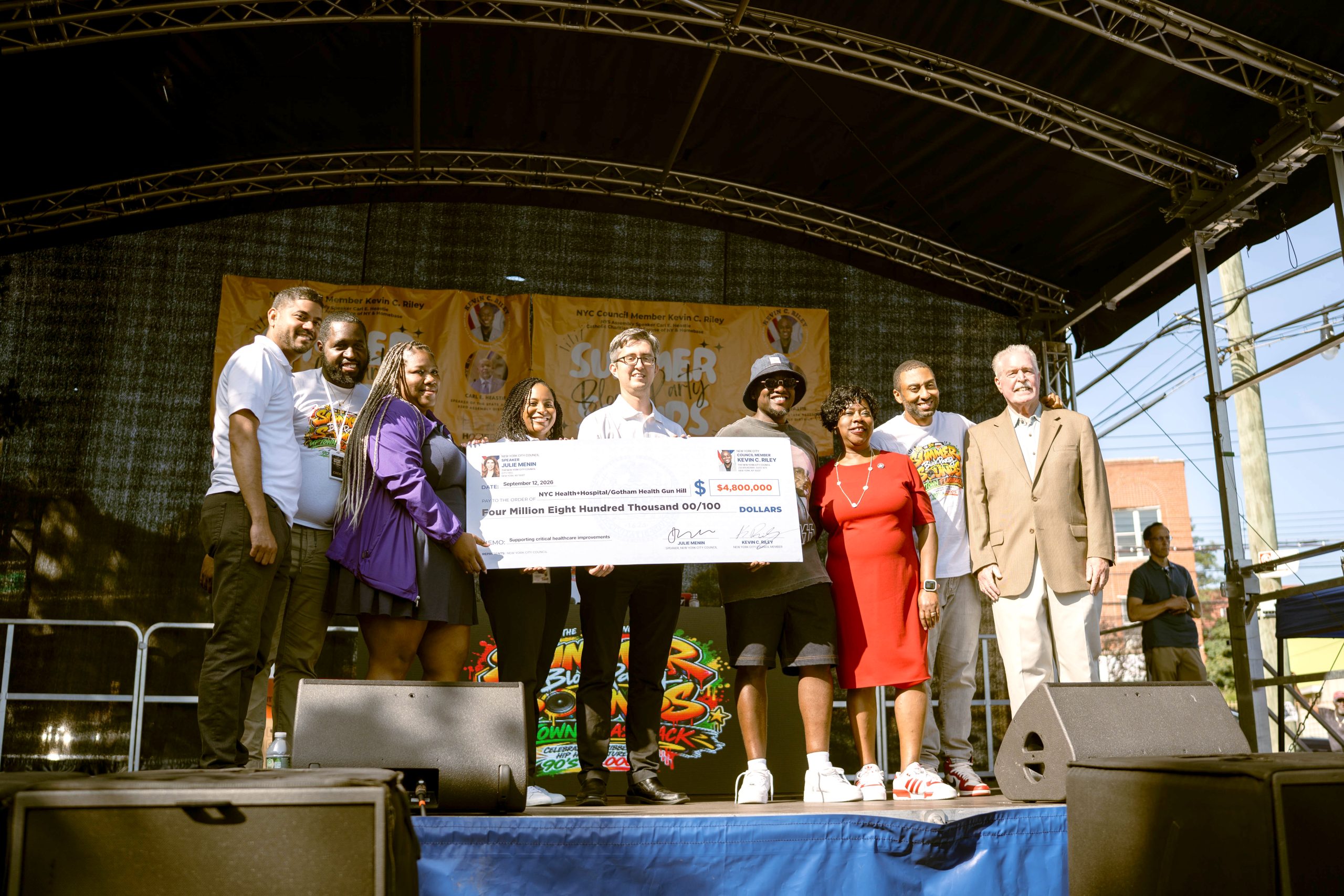 Gotham Health Regional Medical Director Dr. Jeremy O’Connor and Regional Administrator Cari Harewood receive a $4.8 million capital funding check from Council Member Kevin C. Riley to support improvements at Gotham Health, Gun Hill.