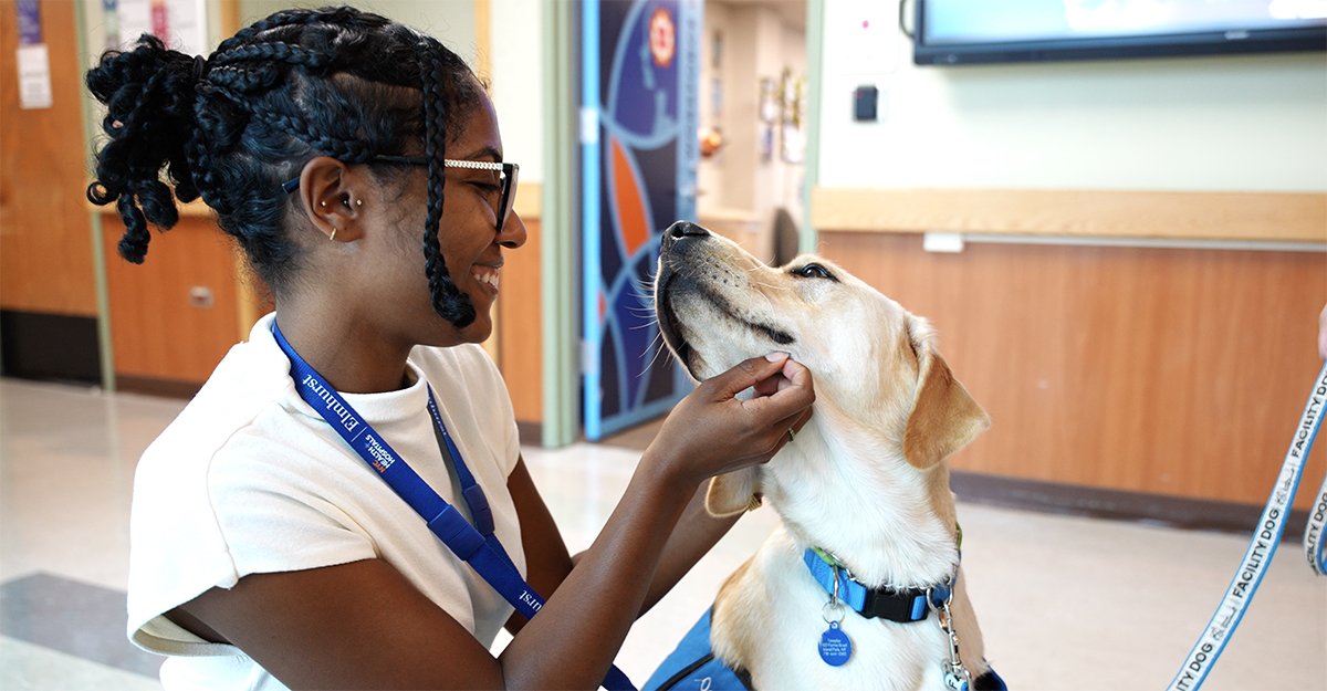 An Elmhurst Hospital volunteer interacts with Weasley outside of the Employee Wellness Center.