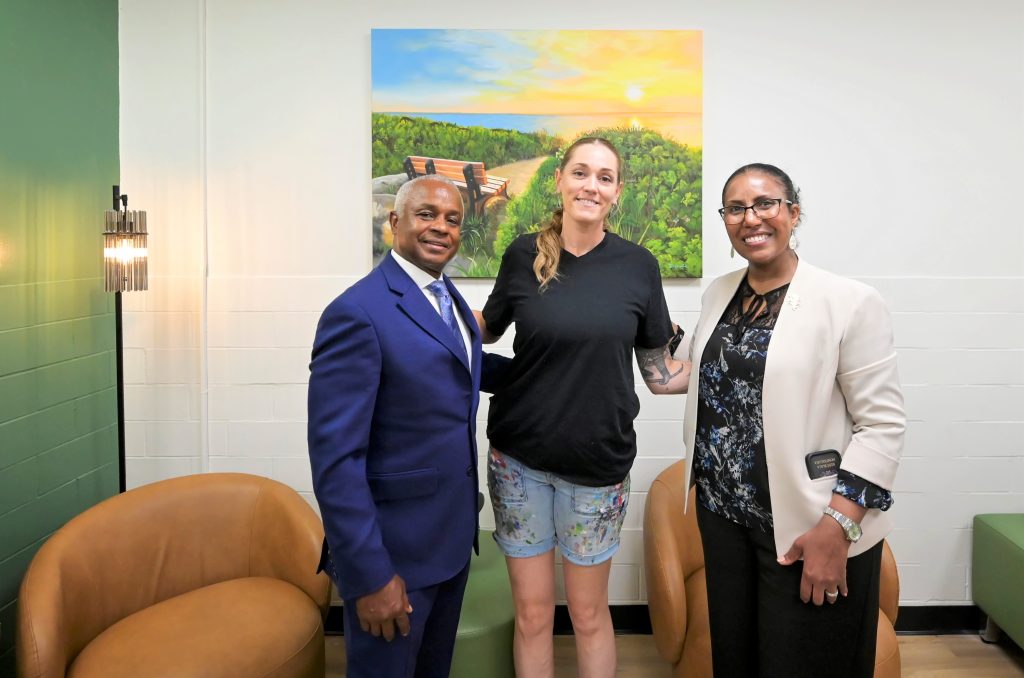 Metropolitan Hospital CEO Julian John and COO Elsa Cosme join muralist Kristy McCarthy in the new Serenity Room, which features her landscape paintings. Photo by Damien Kim.